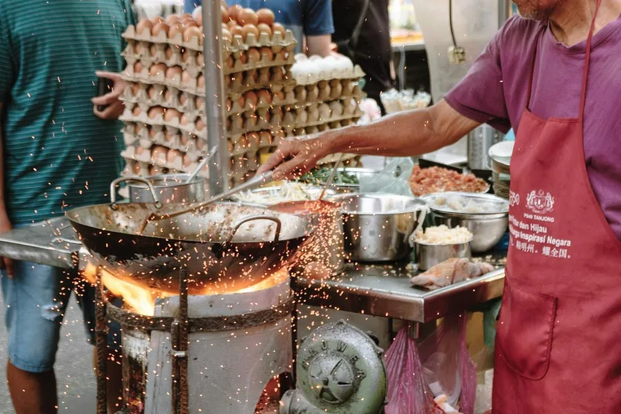 street food vendor frying char koay teow with a wok on a high heat temperature