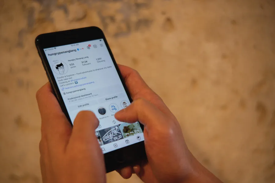 hands sliding on a smartphone with the screen showing Hungry Penang Lang's instagram