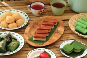 various traditional kuih served on plates and displayed on a bamboo table