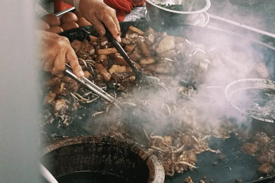 street food vendor frying rice cakes over a high temperature wok