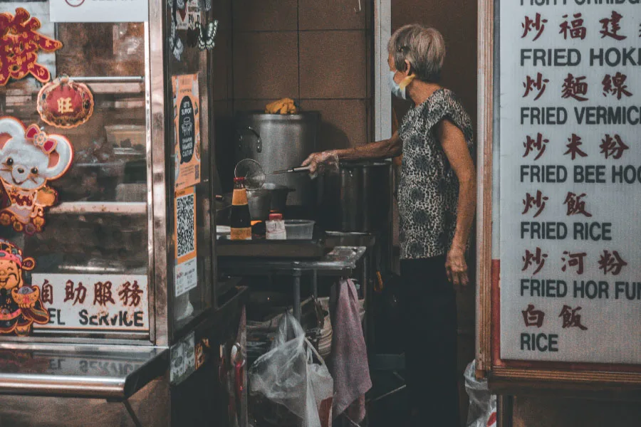 a woman cooking at a local food stall
