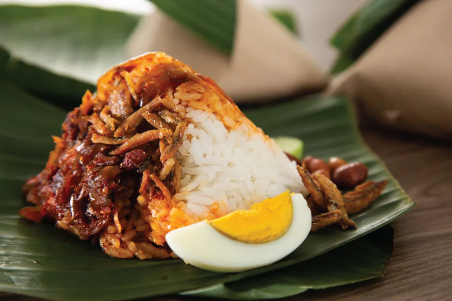 rice, slice of egg, anchovies and curry laid on a piece of banana leaf